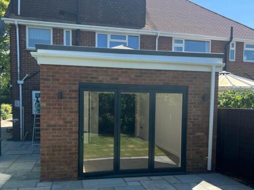 07409baa-44f1-4df3-8dee-a6dca6984b9f-optimized Brick-built rear extension with flat roof and floor-to-ceiling black aluminium doors.