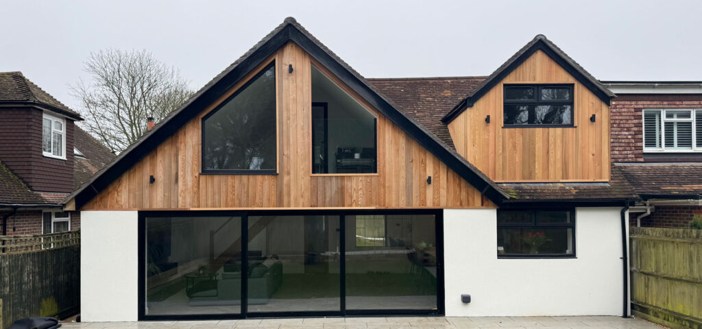 Timber and white render extension with pitched roof and bifold doors.