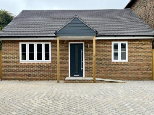 cd347008-6aea-4e72-9271-8142d2b097fe-optimized Single-storey brick annexe with pitched roof and dark blue front door.