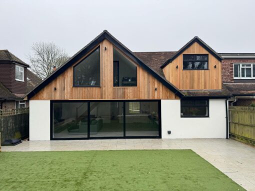 f2b8b206-461e-4b71-ab30-7bc80b5ce683-optimized Contemporary gable-front home with timber cladding and large sliding glass doors.