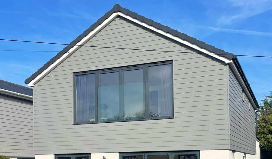 Two-storey loft conversion with grey cladding and full-height windows for added space.