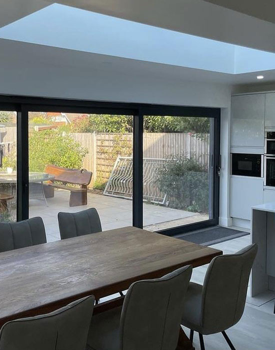 img-windows-doors-2-550-700 Open-plan kitchen dining area with large patio doors and garden views, ideal for family living