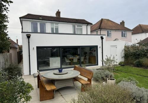 Rear view of completed home extension in Adversane featuring bi-fold doors and new patio area.