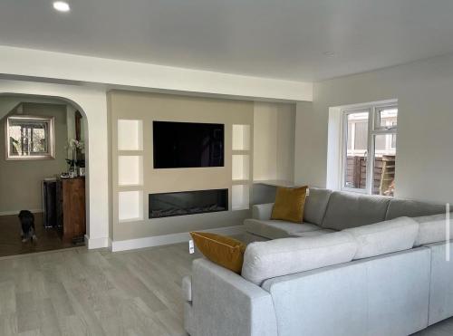 Renovated living room with media wall and corner sofa – part of a full home renovation in Adversane, West Sussex.