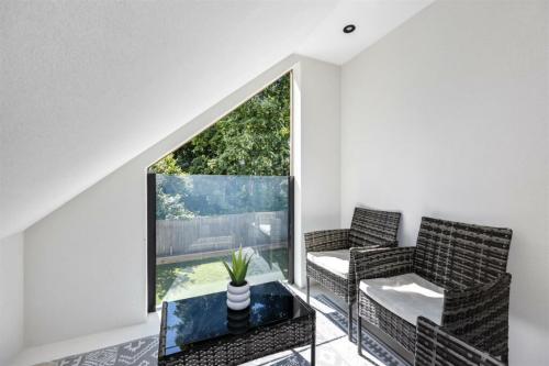 Stylish loft room with sloped ceiling and glass Juliet balcony in Aldsworth home renovation.