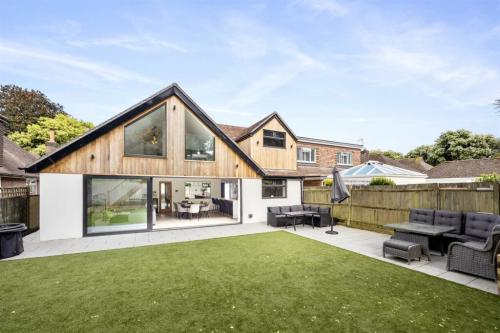 Rear view of completed home extension and loft conversion in Aldsworth with timber cladding and floor-to-ceiling glass.