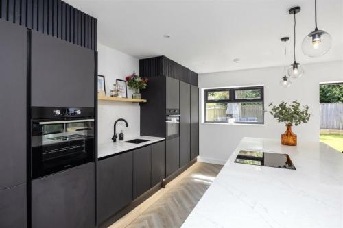 Contemporary black kitchen with marble worktop in Aldsworth renovation by Sussex building contractors.