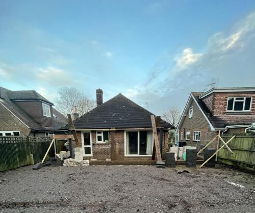 Front exterior of Aldsworth bungalow at foundation and structural prep stage for home extension.