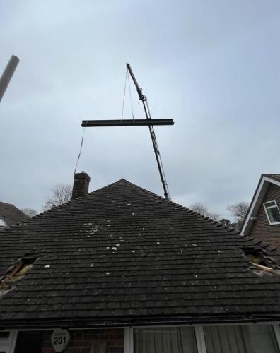 Steel beam being craned onto roof for loft conversion project in Aldsworth near Worthing – structural stage of major renovation.