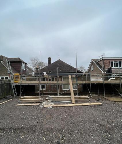 Initial phase of major home renovation in Aldsworth with raised foundations and scaffolding for structural extension.