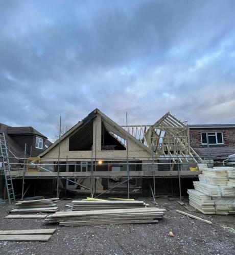 Evening view of ongoing Aldsworth loft build with front-facing gable structure and roof frame in progress.