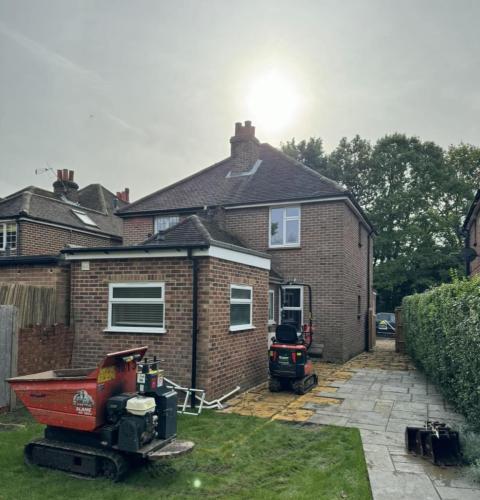 Completed rear extension in Fenns Lane with compact brick build and mini digger on-site for landscaping work.