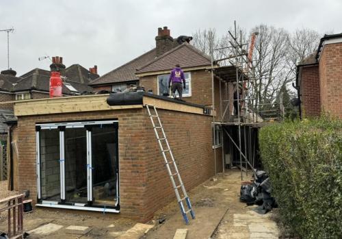 Extension build in progress in Fenns Lane with brick walls and roof structure installation.