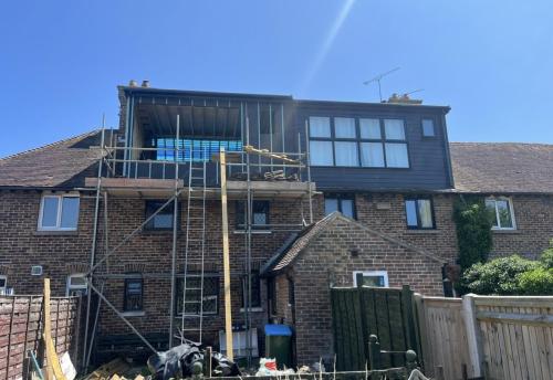 Three-storey rear dormer loft conversion under construction on Fitzalan Road with scaffolding and full-width glazing.
