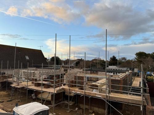 Scaffolded brick structure forming ground floor of new build homes in Worthing residential development project.