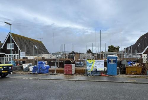 Early construction stage for detached houses in Worthing with site materials, fencing, and promotional signage visible.
