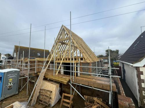 Scaffolded timber roofing in progress for multiple detached homes in Worthing residential development.