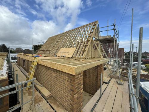 Close-up of pitched roof and brick wall construction for new build home on residential site in Worthing.