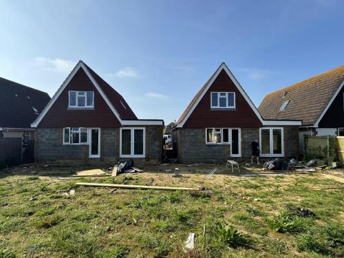 Rear view of two detached houses in North Avenue, Worthing, during final landscaping and exterior works.