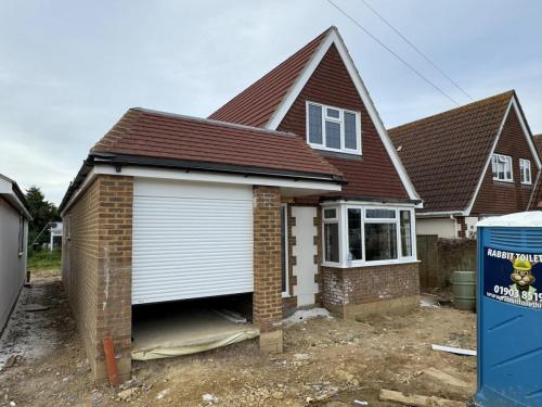 Front view of detached new build property on North Avenue, Worthing, with roller garage door and brick façade.