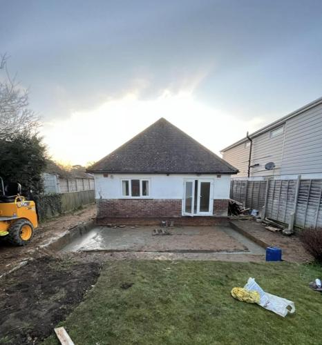 Ground preparation for rear extension at Ocean Drive bungalow in Worthing, with machinery on-site for foundation works.
