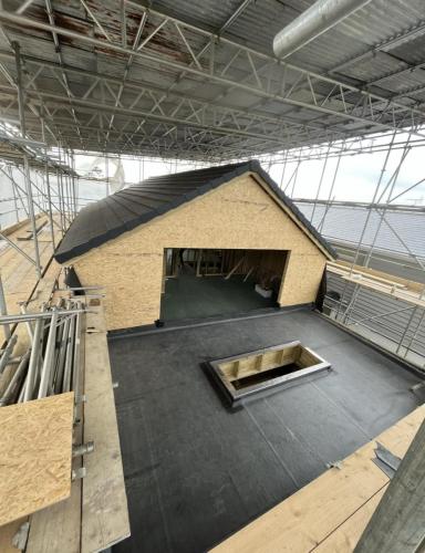 Loft extension underway in Ocean Drive project – pitched roof construction with skylight opening in coastal property.