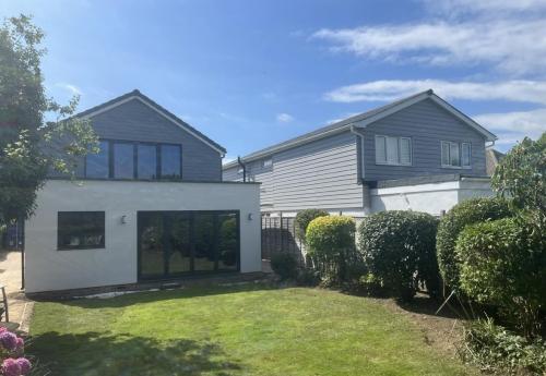 Two-storey rear extension on Ocean Drive home with black-framed sliding doors and light render finish.