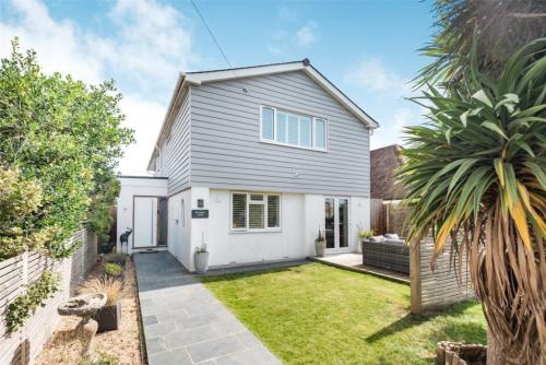 Front view of renovated detached home on Ocean Drive, Worthing, with grey cladding and landscaped front garden.